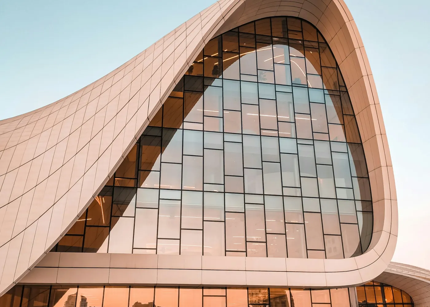 A curved copper-toned roof over a glass facade